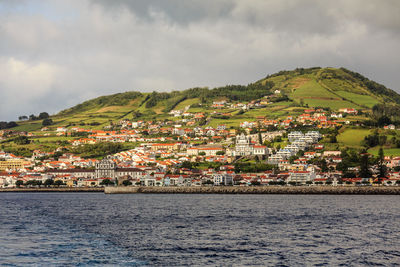 Scenic view of town by sea against sky