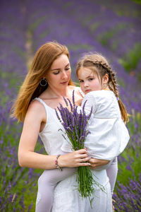Mother showing flower to girl on field