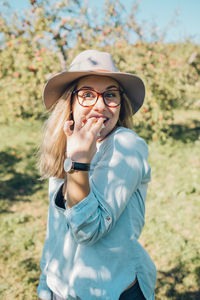 Portrait of woman eating food against trees