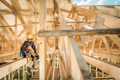 Carpenter sitting on wooden beam at construction site