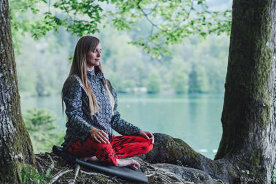 Young woman meditating while sitting in park