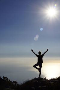 Silhouette man standing on shore against sky during sunset