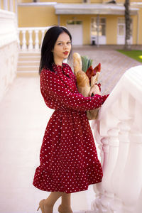 Portrait of young woman standing against building