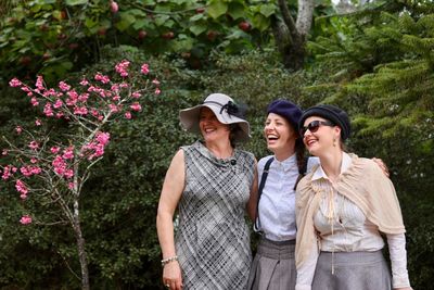 Mother and daughters standing against plants