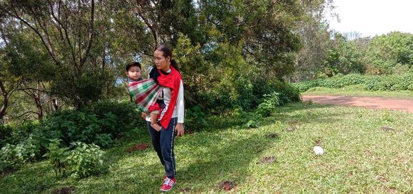 Rear view of mother and son standing on tree