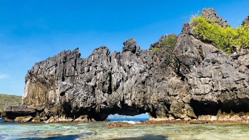 Scenic view of rocks in sea against blue sky