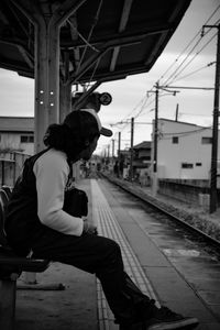 Side view of man skateboarding at railroad station against sky