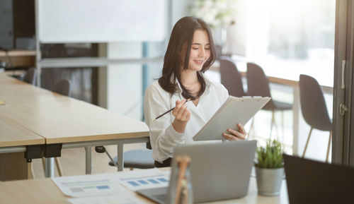 Young woman using phone on table