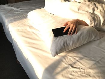 High angle view of person holding phone on bed at home