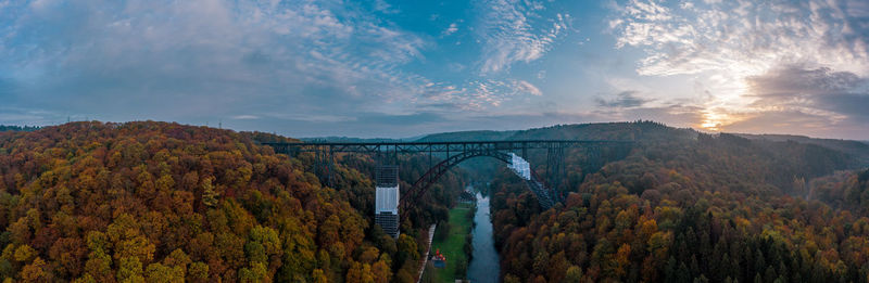 Arch bridge over river against sky during autumn