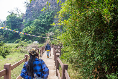 Rear view of man and woman walking on footbridge