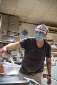 Focused female cook weighing sugar on scales while preparing ingredients for baking bread