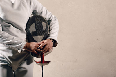 Midsection of woman holding weapon against wall