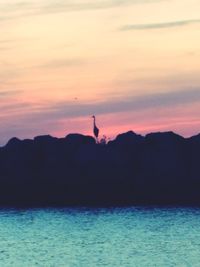 Silhouette of sea against cloudy sky during sunset