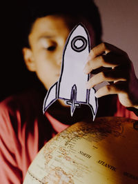 Close-up of boy playing a space ship card next to a earth globe