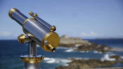 Close-up of coin-operated binoculars by sea against sky