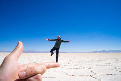 Full length of man with arms raised against clear sky