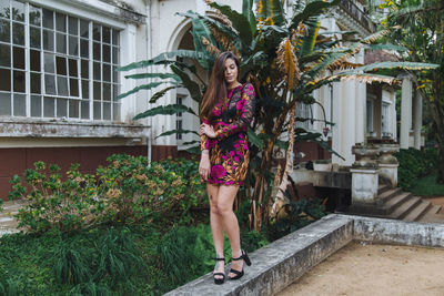 Full length portrait of woman standing against plants