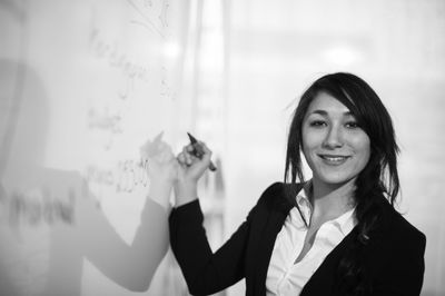 Portrait of woman writing on white board