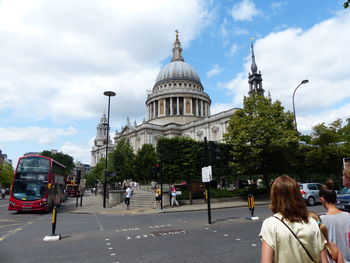 People on street by st paul cathedral against sky