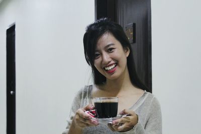 Close-up portrait of smiling young woman holding drink