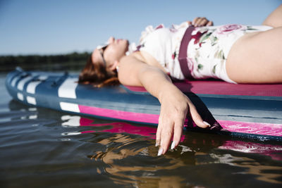 Woman relaxing on sup board in lake