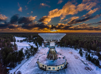 Frozen satellite dish against sky during sunset