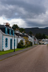 Road by buildings in city against sky