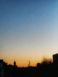 Silhouette buildings against clear sky at sunset