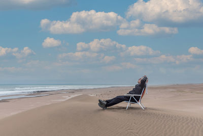 Adult male reclining on a beach lounger in front of the sea