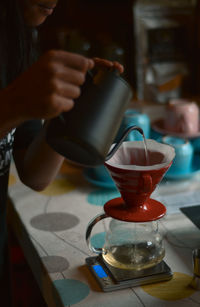 Midsection of woman holding coffee cup on table