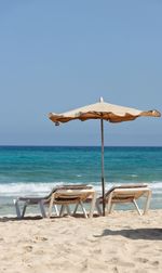Deck chairs on beach against clear sky
