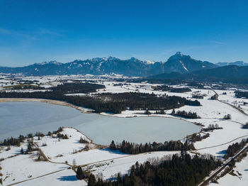 Scenic view of lake by snowcapped mountains against blue sky