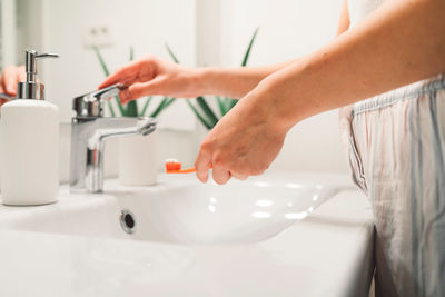 Cropped hand of woman washing hands in bathroom