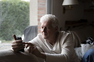 Man using mobile phone while sitting on sofa at home