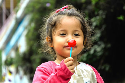 Portrait of cute girl holding lollipop outdoors