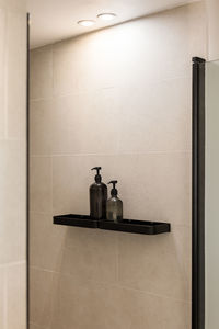 Bottles of gel and shampoo in modern shower with beige wall. minimalist bathroom interior