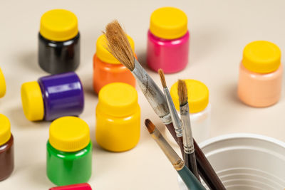 Artistic brushes for painting in pot with gouache paints blurred in the background