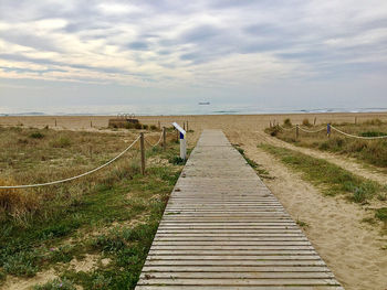 Boardwalk leading towards landscape against sky