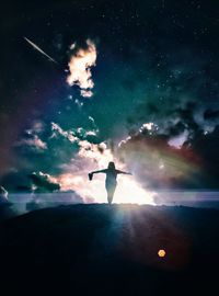 Silhouette woman with arms outstretched standing on field against cloudy sky at night