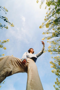 Low angle view of man standing by tree against sky
