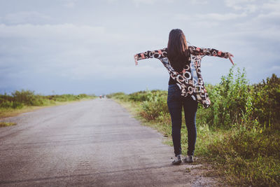 Rear view of woman walking on road against sky