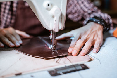 Midsection of man sewing machine