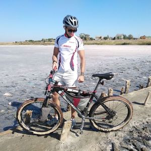 Man riding bicycle on shore against sky