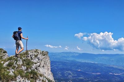 Man standing on rock against sky