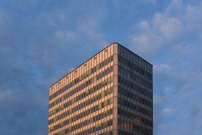 Low angle view of modern building against cloudy sky