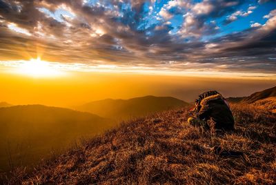 Hiker sitting on mountain during sunset