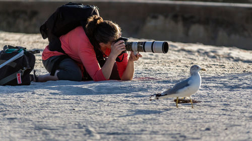 Side view of woman photographer with a seagull right next to her