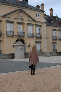 Full length rear view of woman walking on street against building