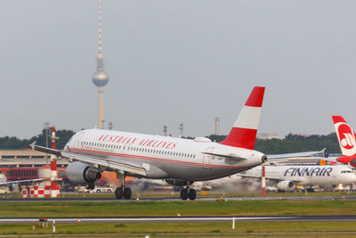 Airplane flying over airport runway against sky